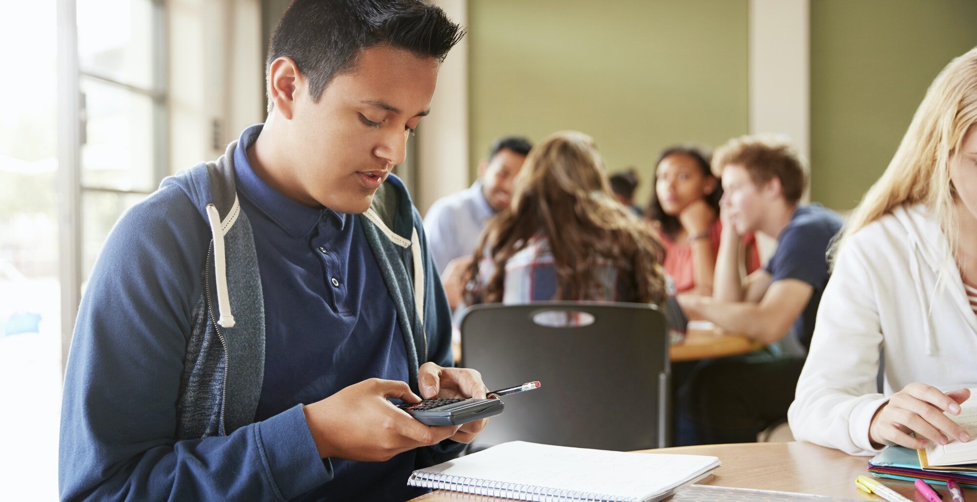 Male High School Student With Calculator Working At Desk